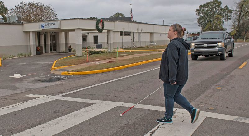 Jay resident Crystal Flannigan, who is visually impaired, crosses Highway 89 near Jay Hospital on Dec. 5, 2025. Flanagan and other Jay residents question the lack of safety devices for visually impaired people on the busy thoroughfare.