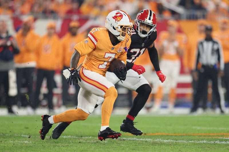 Dec 11, 2025; Tampa, Florida, USA; Tampa Bay Buccaneers running back Bucky Irving (7) runs the ball against Atlanta Falcons safety Xavier Watts (31) during the first quarter at Raymond James Stadium. Mandatory Credit: Nathan Ray Seebeck-Imagn Images