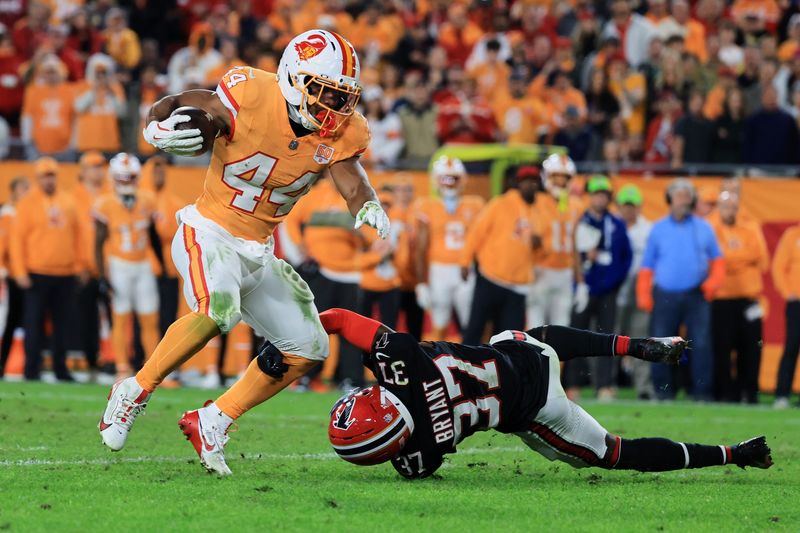 Dec 11, 2025; Tampa, Florida, USA; Tampa Bay Buccaneers running back Sean Tucker (44) breaks a tackle against Atlanta Falcons cornerback Cobee Bryant (37) during the third quarter at Raymond James Stadium. Mandatory Credit: Kim Klement Neitzel-Imagn Images