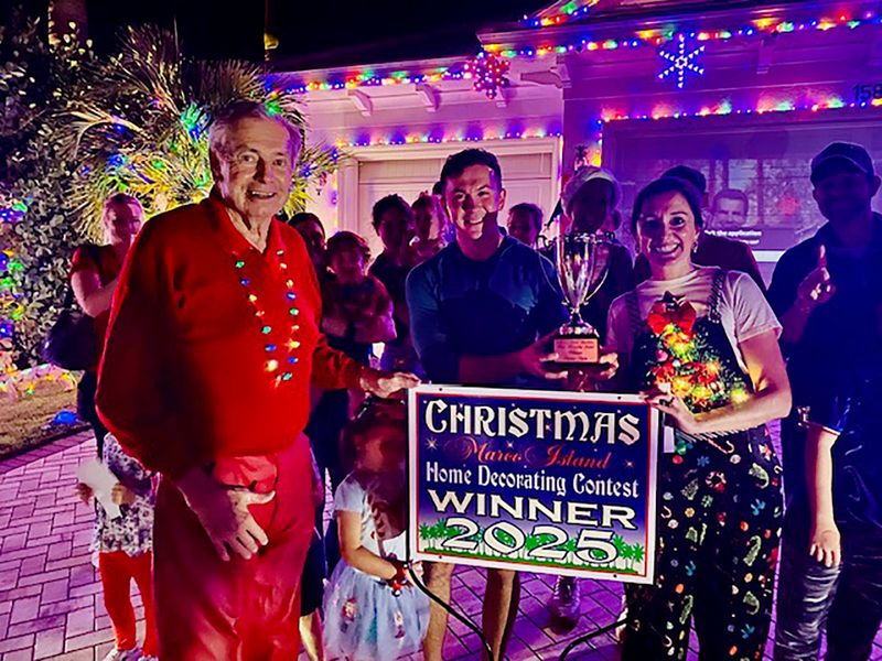 The Turics receive their 2025 Winner yard sign, Traveling Trophy, and Winner Plaque from Dave Rice, chairman, and the House Decorating Committee following the Trolley Ride Judging on Dec. 19.
