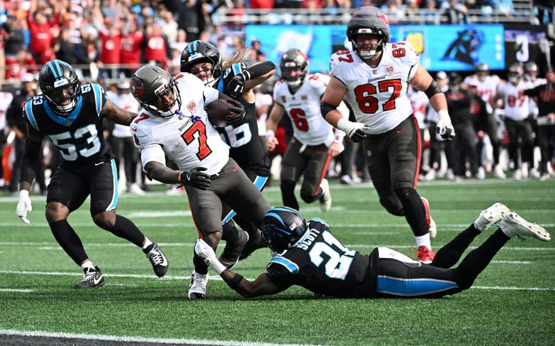 Dec 21, 2025; Charlotte, North Carolina, USA; Tampa Bay Buccaneers running back Bucky Irving (7) runs against Carolina Panthers safety Nick Scott (21) and linebacker Christian Rozeboom (56) during the first half at Bank of America Stadium. Mandatory Credit: Bob Donnan-Imagn Images