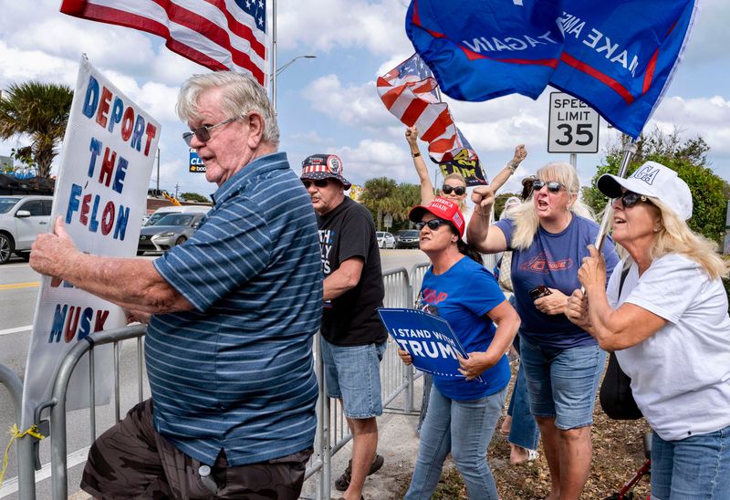 Trump supporters yell insults at Jack Cooperrider, left, while the crowd waits for President Trump's motorcade to pass by after he arrived on March 28 at Palm Beach International Airport.