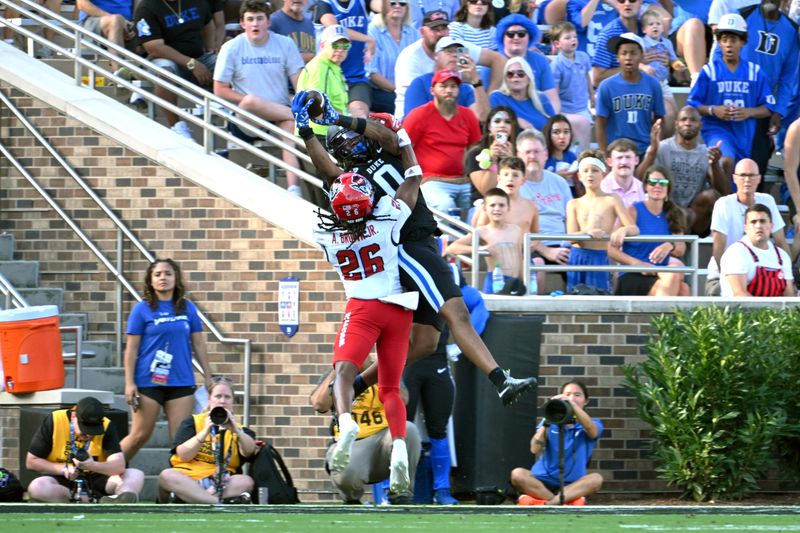 Sep 20, 2025; Durham, North Carolina, USA; Duke Blue Devils cornerback Chandler Rivers (0) catches a touchdown pass against North Carolina State Wolfpack defensive back Asaad Brown Jr. (26) during the second quarter at Wallace Wade Stadium. Mandatory Credit: Zachary Taft-Imagn Images