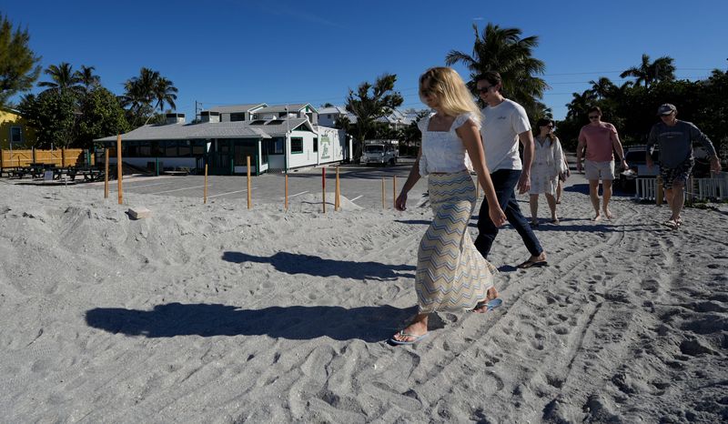 Beachgoers walk along the beach access path across from The Mucky Duck. The iconic restaurant is expected to open this month.