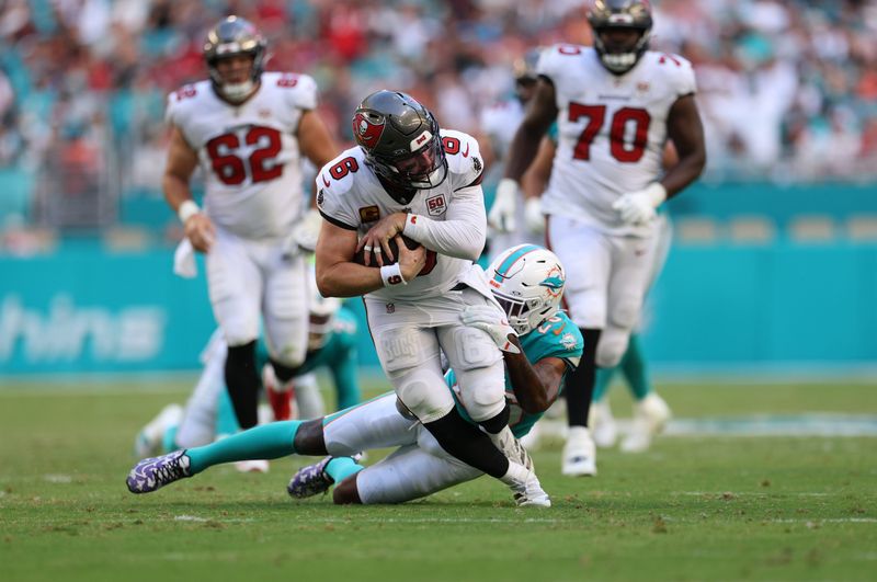 Dec 28, 2025; Miami Gardens, Florida, USA; Tampa Bay Buccaneers quarterback Baker Mayfield (6) is tackled by Miami Dolphins cornerback Rasul Douglas (26) during the third quarter at Hard Rock Stadium. Mandatory Credit: Nathan Ray Seebeck-Imagn Images