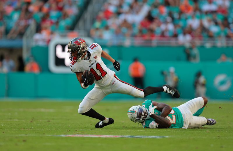 Dec 28, 2025; Miami Gardens, Florida, USA; Tampa Bay Buccaneers wide receiver Jalen McMillan (11) runs for a gain past Miami Dolphins cornerback Rasul Douglas (26) during the fourth quarter at Hard Rock Stadium. Mandatory Credit: Sam Navarro-Imagn Images