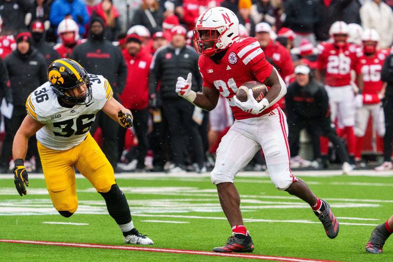 Nov 28, 2025; Lincoln, Nebraska, USA; Nebraska Cornhuskers running back Emmett Johnson (21) runs against Iowa Hawkeyes linebacker Jayden Montgomery (36) during the first quarter at Memorial Stadium. Mandatory Credit: Dylan Widger-Imagn Images