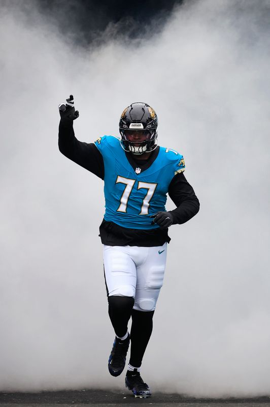 Jacksonville Jaguars offensive tackle Anton Harrison (77) runs onto the field before an NFL football matchup in January.