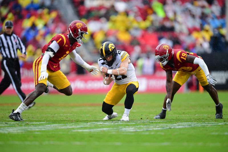 Nov 15, 2025; Los Angeles, California, USA; Iowa Hawkeyes wide receiver Kaden Wetjen (21) runs the ball against Southern California Trojans defensive end Kameryn Crawford (1) and safety Bishop Fitzgerald (19) during the first half at the Los Angeles Memorial Coliseum. Mandatory Credit: Gary A. Vasquez-Imagn Images