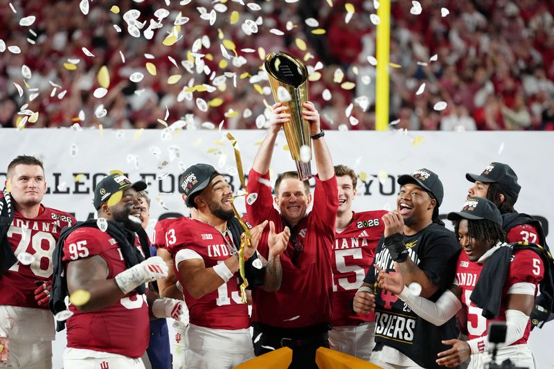 Jan 19, 2026; Miami Gardens, FL, USA; Indiana Hoosiers head coach Curt Cignetti holds up the trophy as the team celebrates winning the College Football Playoff National Championship game at Hard Rock Stadium. Mandatory Credit: Kirby Lee-Imagn Images