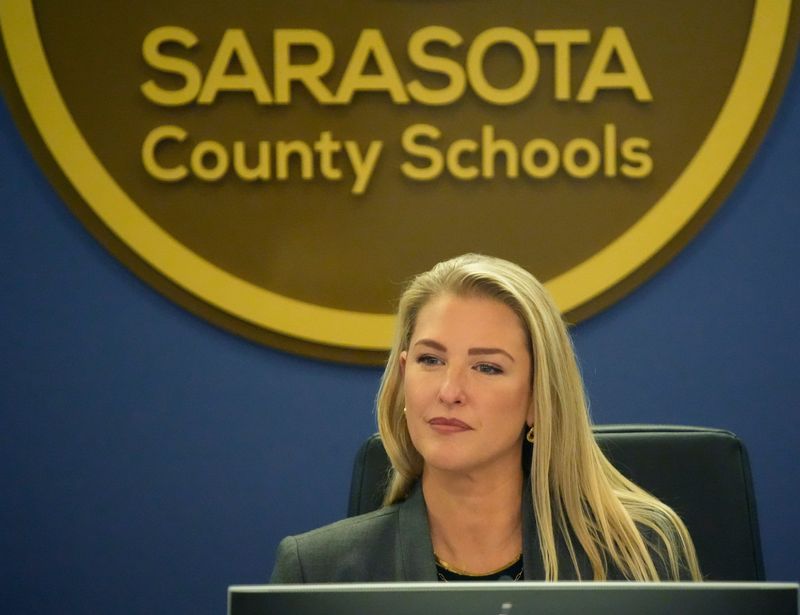 The Sarasota County Schools district logo hovers over the shoulder of School Board Chair Bridget Ziegler during a January 2026 board meeting.