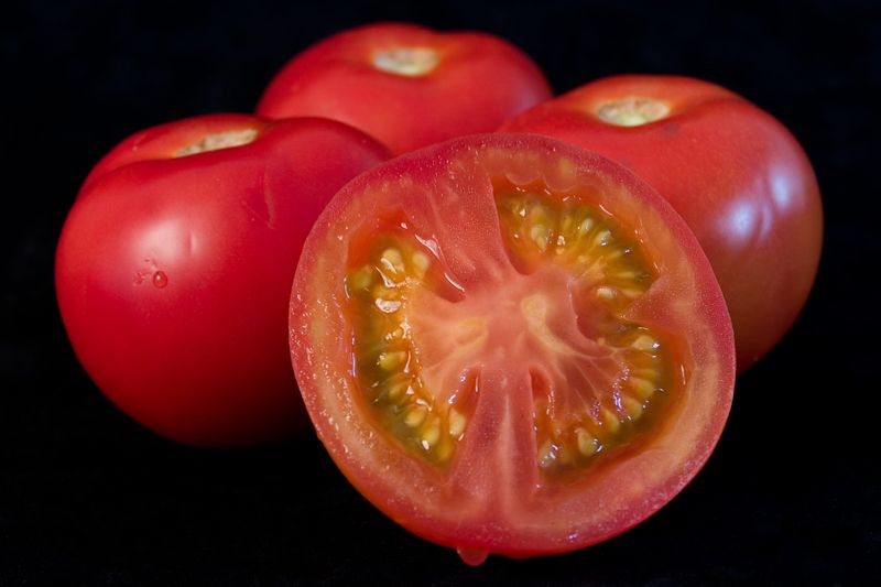 Four red tomatoes, one sliced.