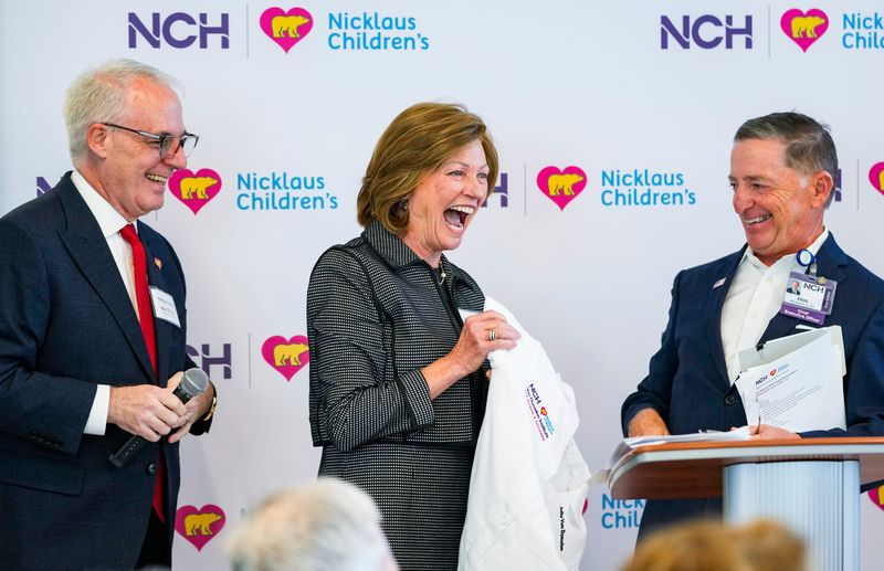 Matthew Love, CEO and president at Nicklaus Children's Health Systems, left, and Paul Hiltz, CEO and president of NCH, present a white coat to Julia Van Domelen during a ceremony to announce a new building offering advanced care for women and children at the NCH North Naples Hospital campus in Naples, Fla., on Tuesday, Jan. 20, 2026.