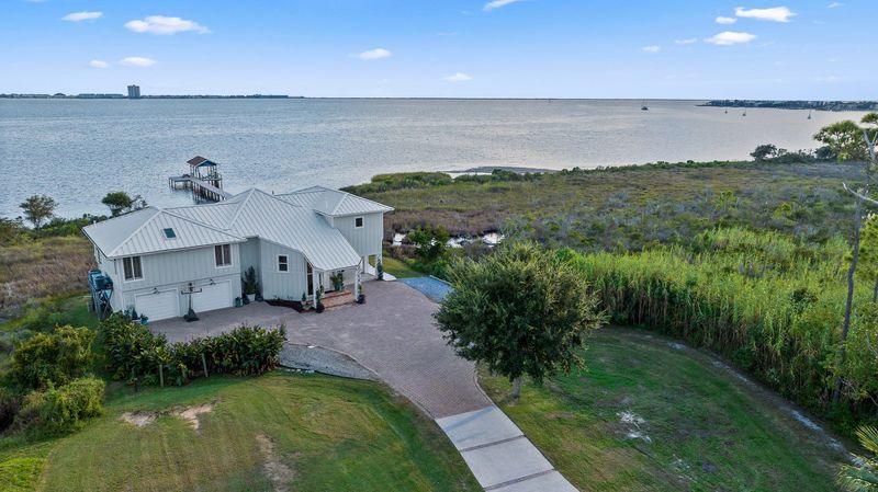 The home is nestled amongst lush greenery, with a private beach and boathouse.