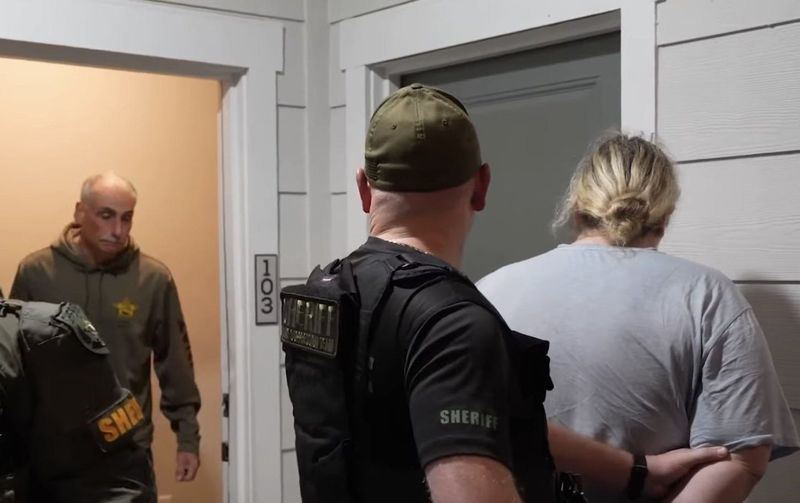 Volusia County Sheriff Mike Chitwood, left, confronts one of his former officers, Amber Williamson, right, as she is handcuffed and held outside her apartment Friday, Jan. 23, 2026, on felony drug trafficking charges. Williamson is a former Daytona Beach Police officer.
