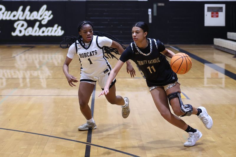 Trinity Catholic Celtics player Alessa Washington (11) drives past Buchholz Bobcats player Jelaiyah Williams (1) during the first half of a basket ball game at Buchholz High School in Gainesville, FL on Thursday, January 29, 2026. [Chris Watkins/Gainesville Sun]