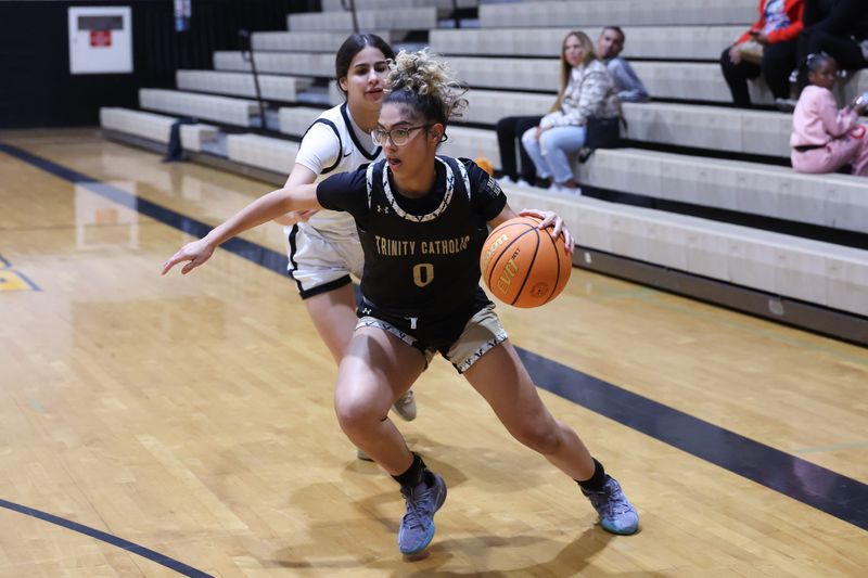 Trinity Catholic Celtics player Izabella Melendez (0) drives past Buchholz Bobcats player Alessia Chaves-Torres, left, during the first half of a basket ball game at Buchholz High School in Gainesville, FL on Thursday, January 29, 2026. [Chris Watkins/Gainesville Sun]