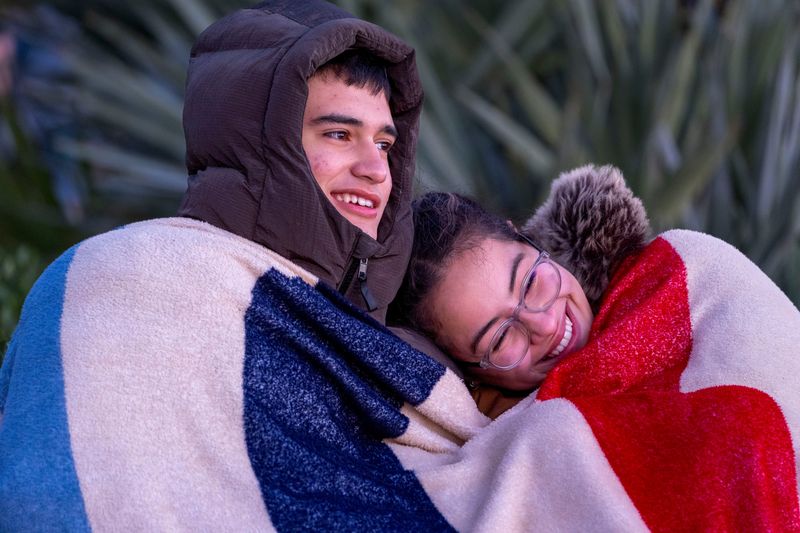 Ian Rodriguez and Jada Castro snuggle in the cold while watching the sun rise on February, 2026, in Palm Beach, Florida.