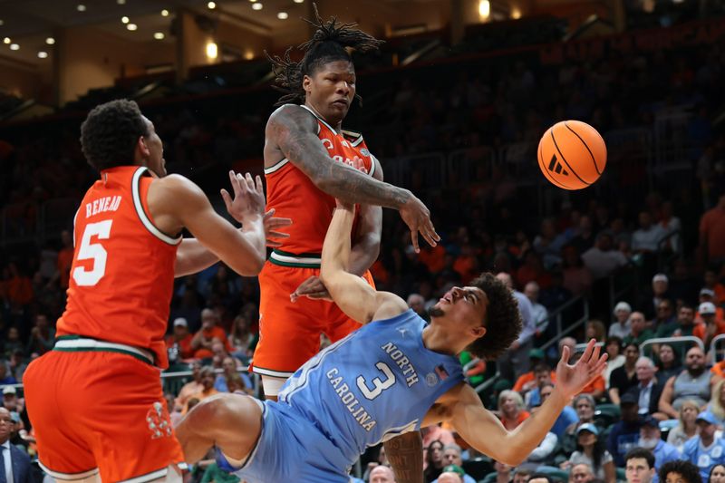 Feb 10, 2026; Coral Gables, Florida, USA; Miami Hurricanes forward Shelton Henderson (7) blocks a shot against North Carolina Tar Heels guard Derek Dixon (3) during the second half at Watsco Center. Mandatory Credit: Sam Navarro-Imagn Images