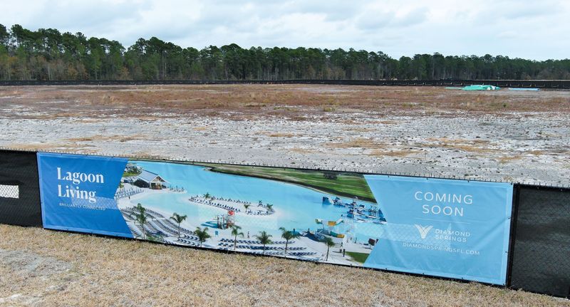 A banner hangs on the fence surrounding where the lagoon area will be built at Diamond Springs, Wednesday morning, February 11, 2026 in Jacksonville, Fla. Metro Development Group is developing the land near Cecil Airport. The lagoon concept is designed for kayaking and swimming, with amenities such as a swim-up bar, a floating obstacle course and a splash pad. [Doug Engle/Florida Times-Union]