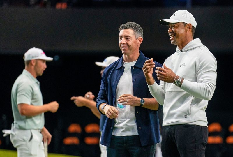 Rory McIlroy and Tiger Woods watch golfers warm up for TGL's inaugural match at SoFi Center in Palm Beach Gardens, Florida.