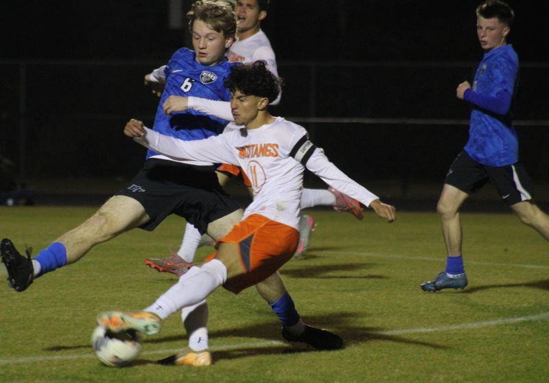 Mandarin forward Robert Calazans (11) shoots as Bartram Trail midfielder Owen Spagna (6) attempts to block during an FHSAA Region 1-6A high school boys soccer semifinal on Feb. 12, 2026. [Clayton Freeman/Florida Times-Union]