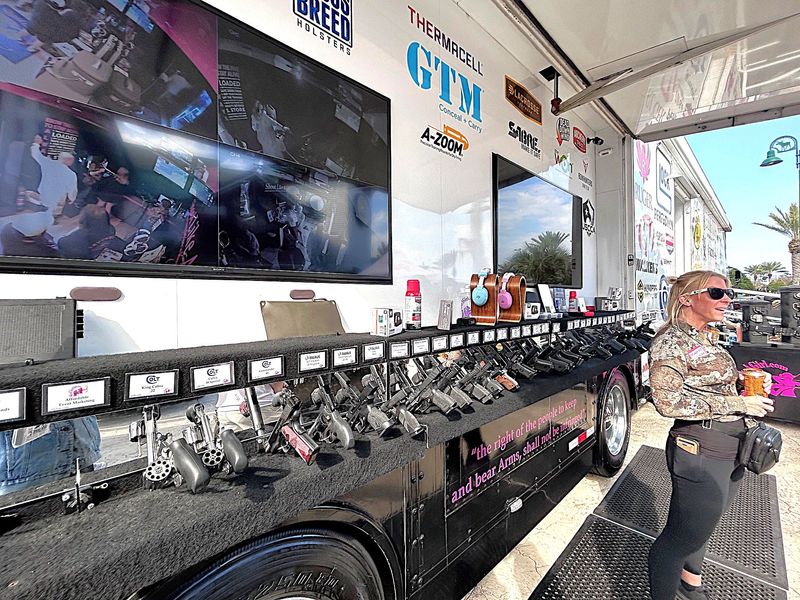 Kelsey Gunn stands by the “gun bar” at the Shoot Like A Girl trailer Thursday, Feb. 12, 2026, by Bass Pro Shops across from Daytona International Speedway in Daytona Beach. Guests can check out different handguns, which have all been deactivated, at the gun bar.