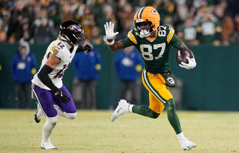Dec 27, 2025; Green Bay, Wisconsin, USA; Green Bay Packers wide receiver Romeo Doubs (87) runs after a catch against Baltimore Ravens safety Alohi Gilman (12) during the second quarter at Lambeau Field. Mandatory Credit: Jeff Hanisch-Imagn Images
