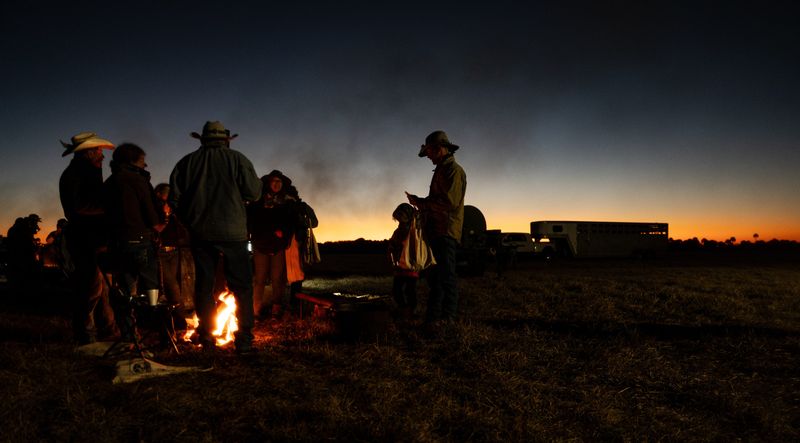 Participants and crew of the Great Florida Cattle Drive 2026 huddle up to a fire on Thursday, Jan. 29, 2026. Temperatures at night were in the 30’s and 40 throughout the reenactment.