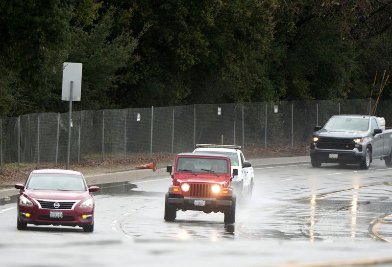 Cars drive along slick roadways like Erbes Road at Avenida de las Flores in Thousand Oaks, on Feb. 16, 2026, during a heavy storm.
