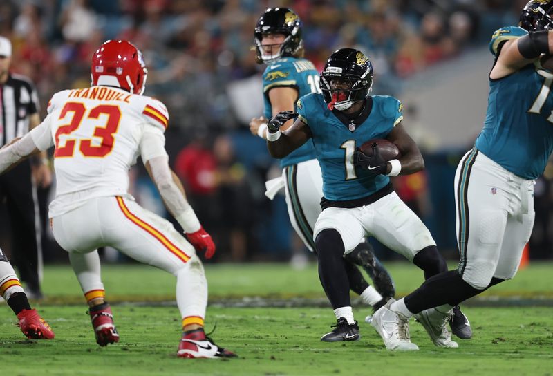 Oct 6, 2025; Jacksonville, Florida, USA; Jacksonville Jaguars running back Travis Etienne (1) runs against Kansas City Chiefs linebacker Drue Tranquill (23) during the first quarter at EverBank Stadium. Mandatory Credit: Morgan Tencza-Imagn Images