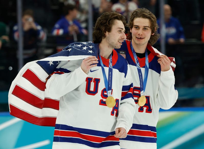Quinn Hughes (43) of the United States and Jack Hughes (86) of the United States celebrate after defeating Canada in the men's ice hockey gold medal game during the Milano Cortina 2026 Olympic Winter Games at Milano Santagiulia Ice Hockey Arena.