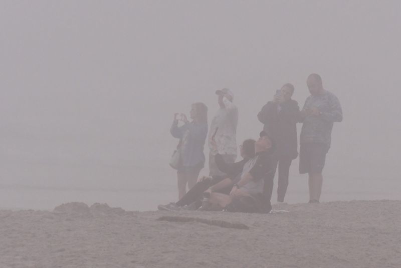 Spectators on the beach stare into a gray wall of fog, hoping for a glimpse or the SpaceX Falcon 9 rocket carrying 29 Starlink satellites into low-Earth orbit on Mission 6-108. The rocket launched at 7:16 a.m. EST on Friday, Feb. 27 from Launch Complex 40 at Cape Canaveral Space Force Station.