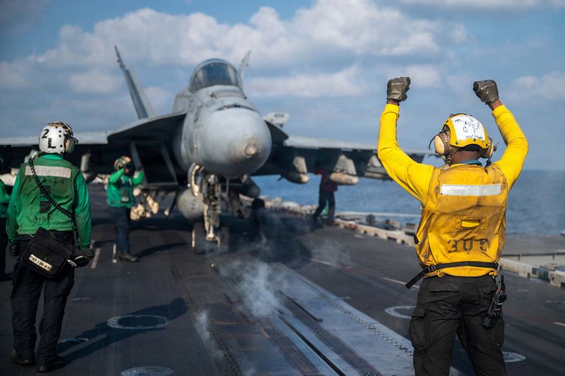 A U.S. Navy sailor signals an F/A-18E Super Hornet on the flight deck of the aircraft carrier USS Abraham Lincoln at an undisclosed location March 4, 2026.