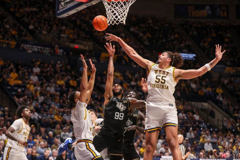 Mar 6, 2026; Morgantown, West Virginia, USA; West Virginia Mountaineers center Harlan Obioha (55) blocks a shot from UCF Knights forward Jordan Burks (99) during the first half at Hope Coliseum. Mandatory Credit: Ben Queen-Imagn Images