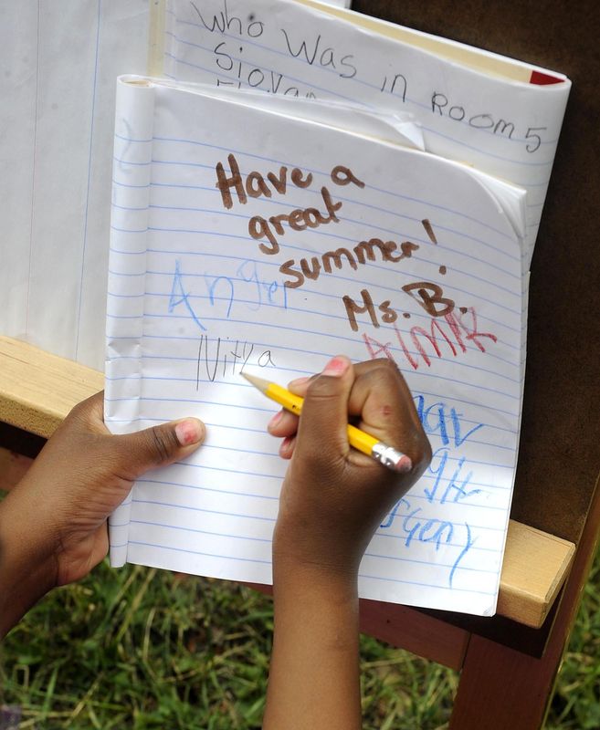 First-grader Nitya Mims, 7, signs a classmate's composition book on the last day of classes for the school year at Edison Elementary School on June 9, 2011.