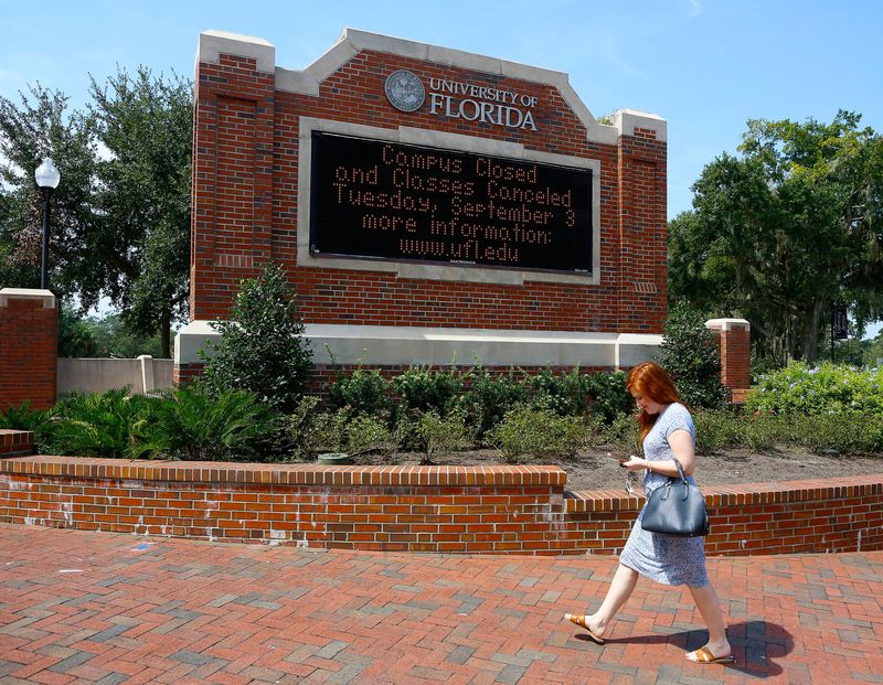 A woman walks past a University of Florida welcome sign on the UF campus off University Avenue, in Gainesville, Fla. September 5, 2019.