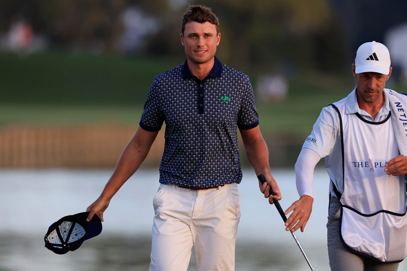 Ludvig Åberg hands off his club to caddie Joe Skovron afting finishing his day on the 18th green during the third round of The Players Championship PGA golf tournament at TPC Sawgrass, Saturday, March 14, 2026, in Ponte Vedra Beach, Fla. [Corey Perrine/Florida Times-Union]