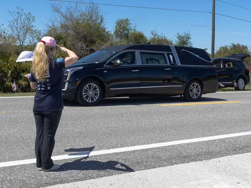 A woman salutes as a hearse carrying the remains of U.S. Army Reserve Major Cody Khork passes on Medulla Road outside Lakeland Linder International Airport. Khork was killed in Kuwait on March 1.