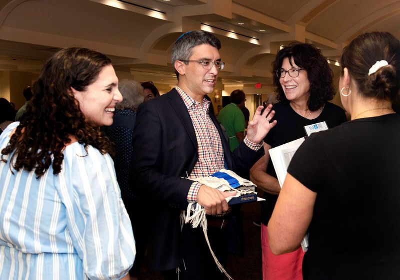 Rabbis Carlie Daniels, from left, and Ryan Daniels speak to member Cindy McDonald and guest Rebecca Steinhouse during the 'ShaBaBeQue' after Shabbat services at Temple Israel on Aug. 18, 2023 in West Palm Beach.