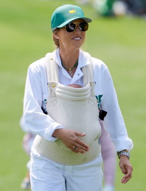Scottie Scheffler's wife, Meredith, carries her son, Remy, as she walks the second hole during the Masters Par 3 Contest on April 8, 2026, at Augusta National Golf Club.