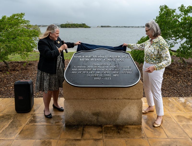 Palm Beach Mayor Danielle Moore, left, and Nina Rumbough unveil a refinished plaque honoring Marjorie Merriweather Post on the causeway near Mar-a-Lago during a rededication ceremony on April 8. Rumbaugh is Post's granddaughter
