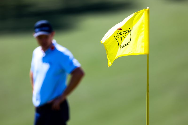 Apr 9, 2026; Augusta, Georgia, USA; The Masters flag stick blows in the wind as Justin Rose surveys the ninth green in the background during the first round of the Masters Tournament at Augusta National Golf Club. Mandatory Credit: Bill Streicher-Imagn Images