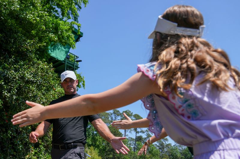 Brooks Koepka high-fives Mary Bracken Green, 10, of Augusta, as he walks to the fifth tee box during the final round of the 2026 Masters Tournament at Augusta National Golf Club.
