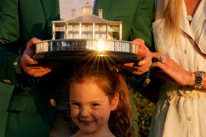 Apr 12, 2026; Augusta, Georgia, USA; Rory McIlroy holds the Masters championship trophy while standing with his wife, Erica Stoll, and his daughter, Poppy, during the green jacket ceremony after the final round of the Masters Tournament at Augusta National Golf Club. Mandatory Credit: Kyle Terada-Imagn Images
