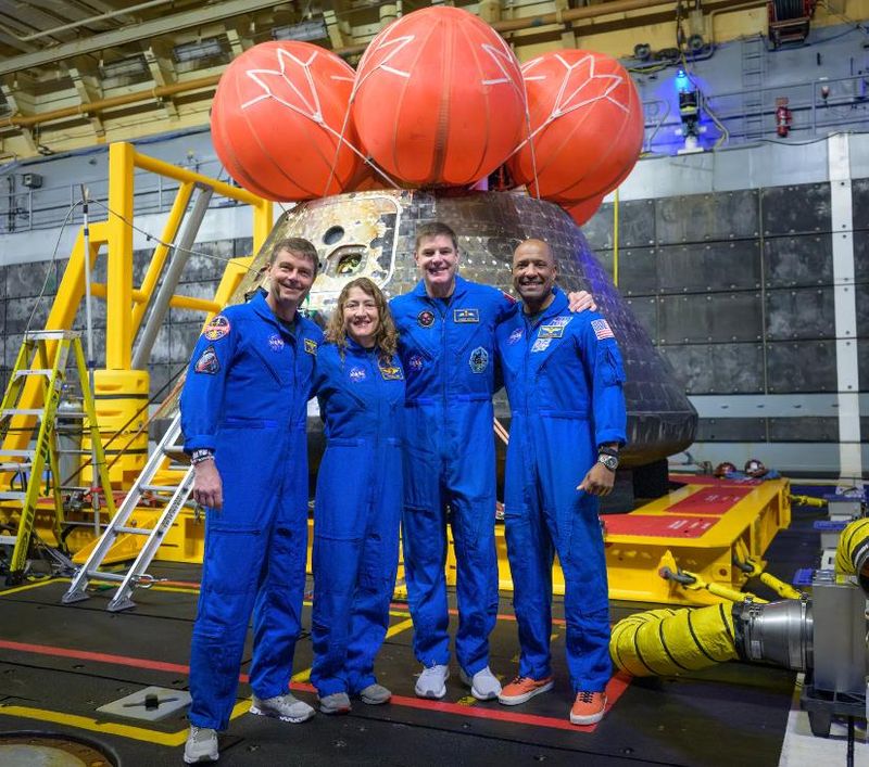 The crew of the Artemis II mission pose with their spacecraft after splashdown.
