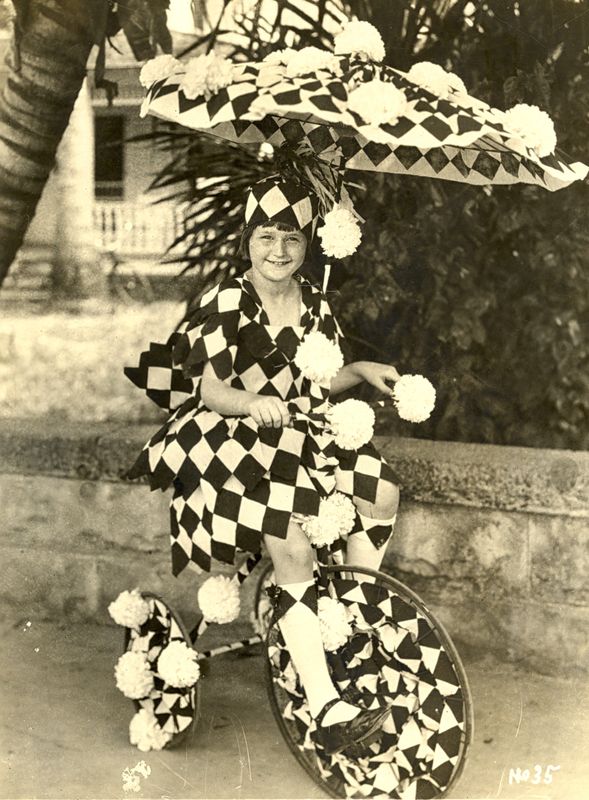 A child in a clown outfit with her decked out tricycle for Seminole Sun Dance.