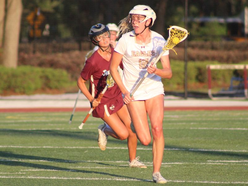 Episcopal midfielder Brooke McCoy (12) advances upfield as St. Augustine's Sarah Accurso (9) pursues during an FHSAA Region 1-1A high school girls lacrosse playoff on April 22, 2026. [Clayton Freeman/Florida Times-Union]