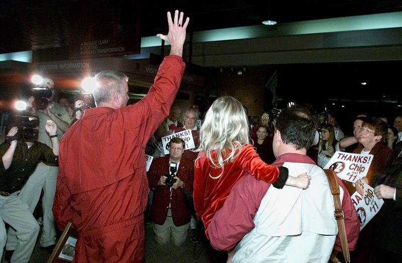 After returning home from a harrowing trip to Stanford, a robust crowd of supporters and the press surround FSU baseball coach Mike Martin (L) and assistant coach Chip Baker (R), holding his 5-year-old daughter Katie, who was sitting on his lap when a bus driver suffered a heart attack and Chip grabbed the wheel.
