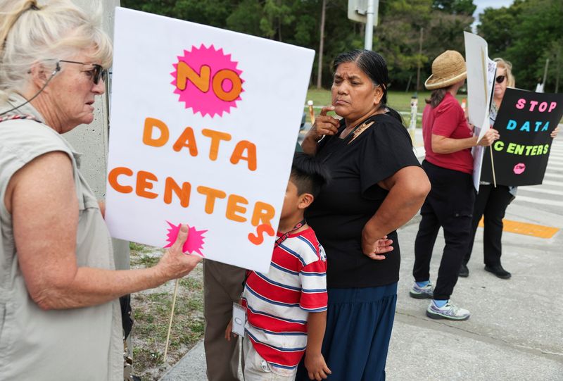 Residents against a data center in Indiantown stand on the corner of Warfield Boulevard and Southwest Adams Avenue before a regular council meeting, April 23, 2026. The Village Council took another step toward adopting an ordinance for a PUD zoning agreement and Master Site Plan and rezoning about 5,700 acres of FPL land that was annexed into the village. Opponents of the ordinance fear a data center could potentially be permitted. The ultimate approval of what gets built is decided with the village staff and not by the Village Council.